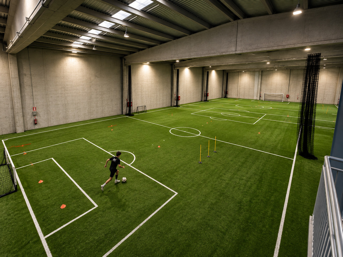 Vista general desde altura de los campos indoor de NEXT en Sabadell con un futbolista entrenando individualmente